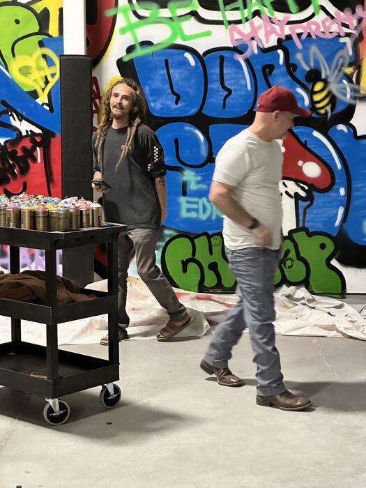 A graffiti artist beside the spray-can cart mid-build