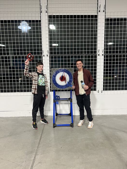 A teen throwing at the axe-throwing target