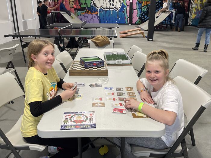 Two teens laughing over a board game at Life Shop