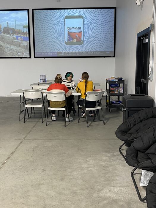 Teens at the tables working while a lesson runs on the big screen
