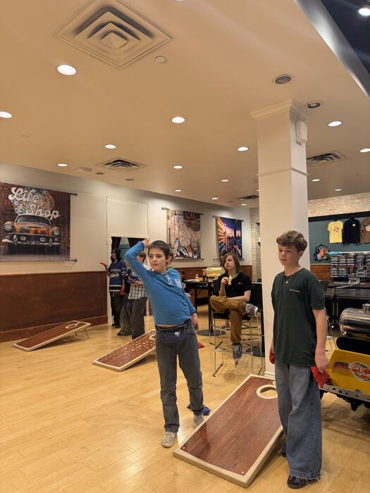Teens playing cornhole together under the Life Shop sign