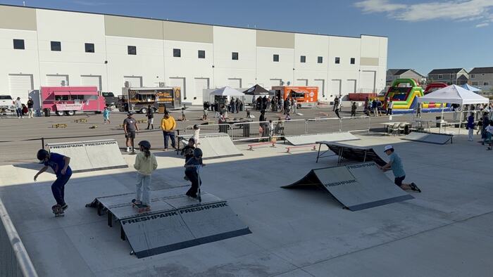 Kids skating and scooting the portable ramps at an outdoor event