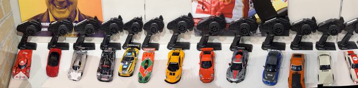 The wall of RC cars with their controllers racked above