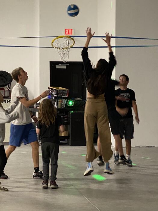 Teens leaping for a volleyball at the net